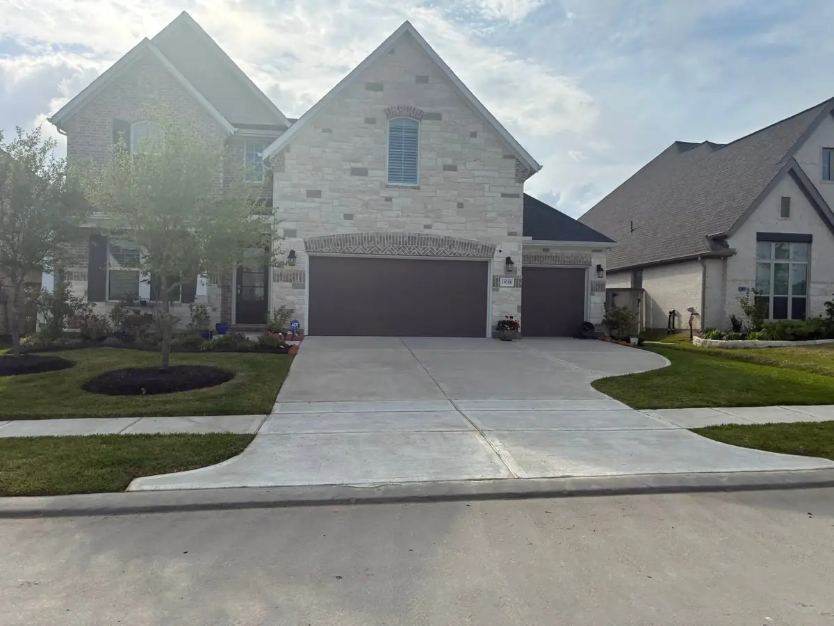 Weed-free front lawn and clean driveway at a stone-front home